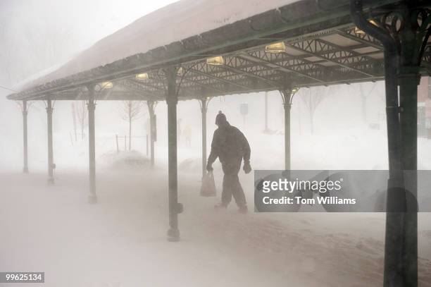 Man braves the wind outside of Eastern Market during a winter storm expected to bring 10-15 inches of snow in the District with gust of winds near 40...