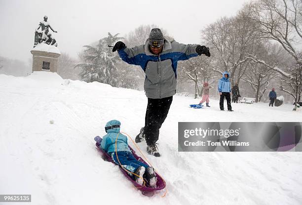 Father pushes his daughter down a hill in Lincoln Park during a winter storm expected to bring 10-15 inches of snow in the District with gust of...