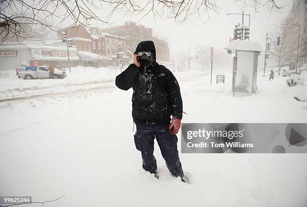 Pedestrian makes a phone call on Massachusetts Ave, NE, during a winter storm expected to bring 10-15 inches of snow in the District with gust of...