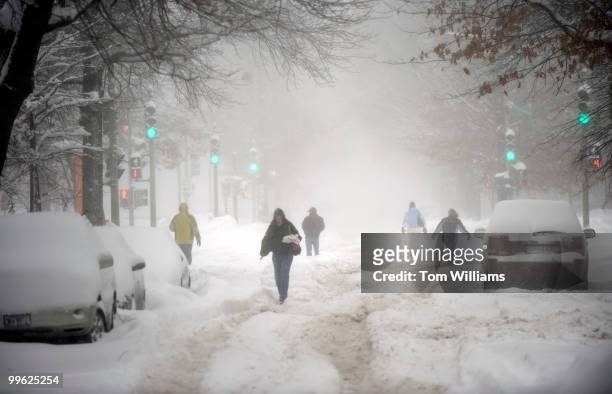 Pedestrians walk in the street and the intersection of 3rd st., and Pennsylvania Avenue, SE, during a winter storm expected to bring 10-15 inches of...