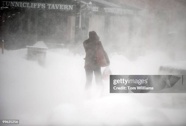 Woman shields herself from the wind on 7th St., SE, during a winter storm expected to bring 10-15 inches of snow in the District with gust of winds...