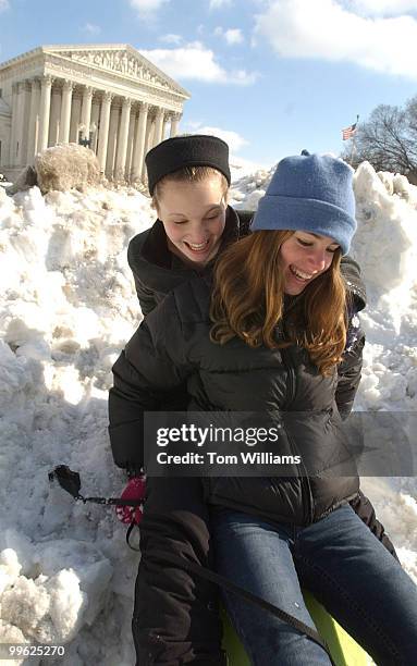 8th graders Dana Bell, right, and Maggie Lange from the District sled down a snow bank near the Supreme Court.