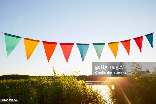 colorful pennant flags for party decoration at lake against sky - slinger decoraties stockfoto's en -beelden