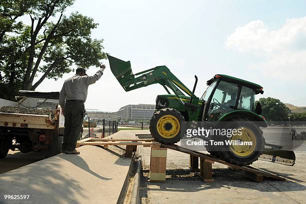 Coleman Washington directs tractor operator Roland Foreman toward a truck that will carry away debris from the Capitol Reflecting pool, during...