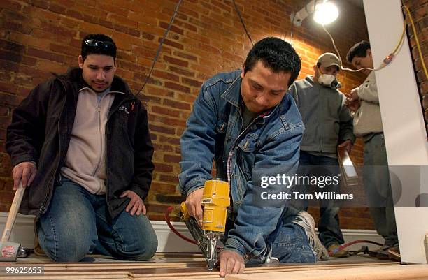 Miguel Mendez installs hardwood floors as Ralph Santos, left, looks on, on the second floor of a townhouse on 6th Street, NW. The house will be...