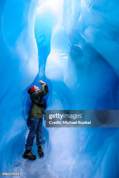 woman photographing in a ice cave in fox glacier, south island, new zealand - westland stock-fotos und bilder