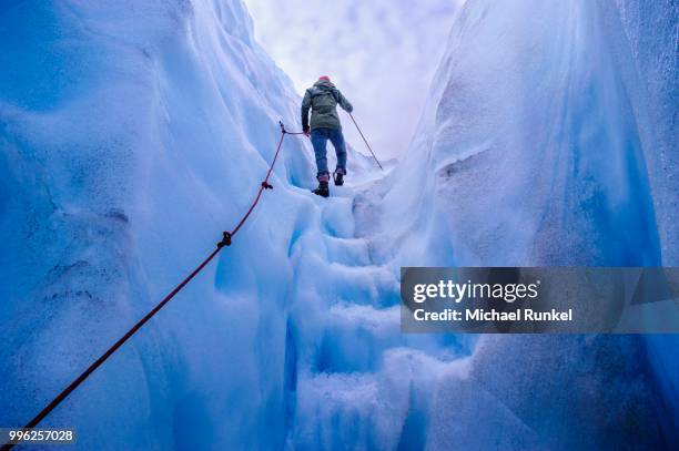 woman walking steps out of a ice cave in fox glacier, south island, new zealand - westland isla del sur de nueva zelanda fotografías e imágenes de stock