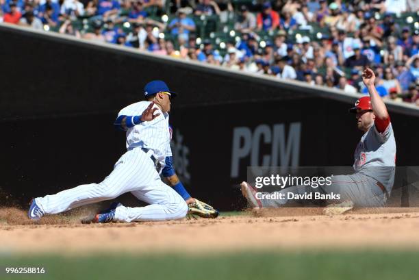 Javier Baez of the Chicago Cubs tries to tag Scott Schebler of the Cincinnati Reds on July 8, 2018 at Wrigley Field in Chicago, Illinois. The Cubs...