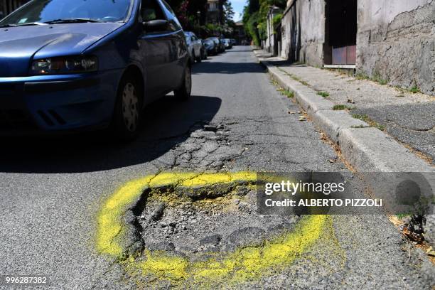 Car passes near a road hole circled with yellow paint in central Rome, on July 11, 2018. - Graziella Viviano, mother of Elena Aubry who died after a...