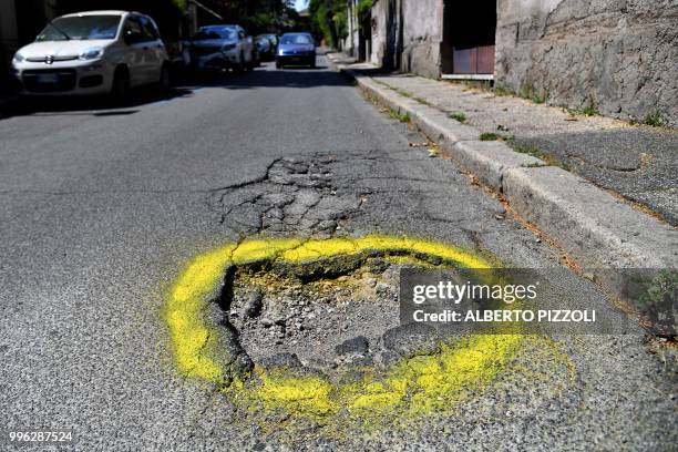 Car passes near a road hole circled with yellow paint in central Rome, on July 11, 2018. - Graziella Viviano, mother of Elena Aubry who died after a...