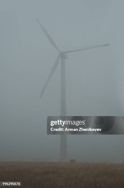 wind turbine in the fog - arman zhenikeyev stock-fotos und bilder