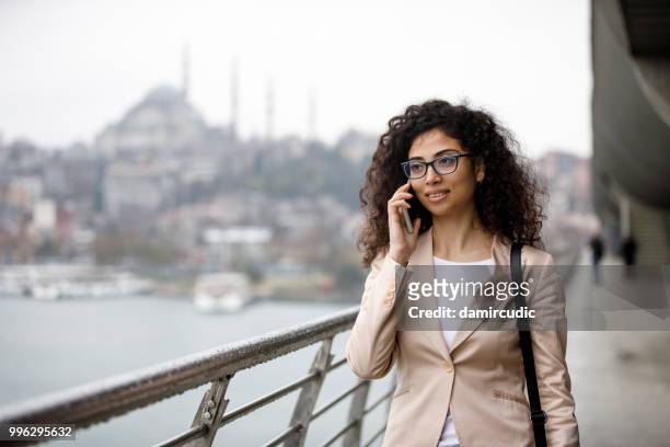 jovem empresária falando ao telefone no meio do rua em istambul, turquia - damircudic - fotografias e filmes do acervo