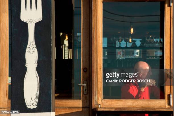 Man eats in a restaurant in Kalk Bay, a trendy fishing village, about 30km from the city centre, on July 11 in Cape Town. - Kalk Bay, with a...
