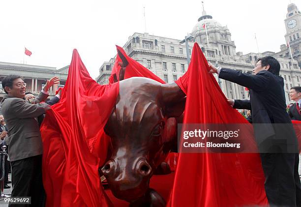 Tu Guangshao, Shanghai's vice mayor, left, and other officials, unveil Arturo Di Modica's Charging Bull statue, a version of which is installed near...