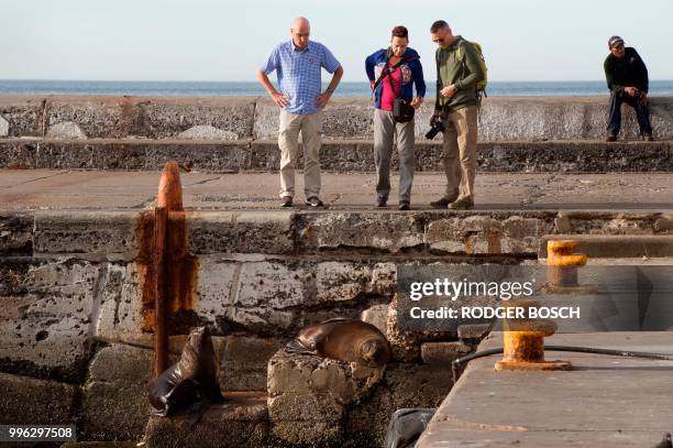 Two women talk on the street in Kalk Bay, a trendy fishing village, about 30km from the city centre, on July 11 in Cape Town. - Kalk Bay, with a...