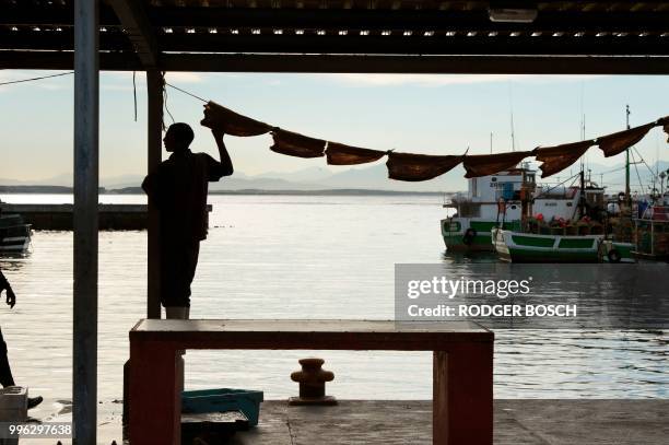 Man hangs out snoek to dry in the harbour in Kalk Bay, a trendy fishing village, about 30km from the city centre, on July 11 in Cape Town. - Kalk...