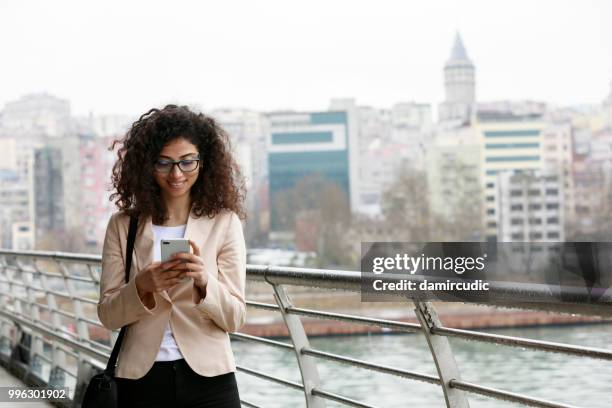 mulher jovem, checando o celular na cidade - damircudic - fotografias e filmes do acervo