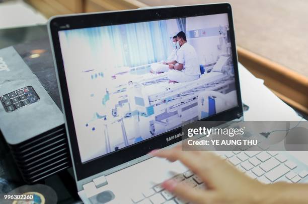 Local government workers use a laptop to project newly released video footage of the 12 resued "Wild Boars" by Thai government public relations...