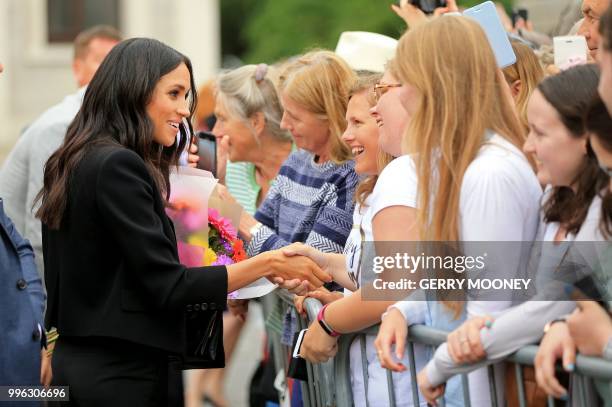 Britain's Meghan, Duchess of Sussex greets well-wishers after her visit with Britain's Prince Harry, Duke of Sussex to Trinity College in Dublin on...