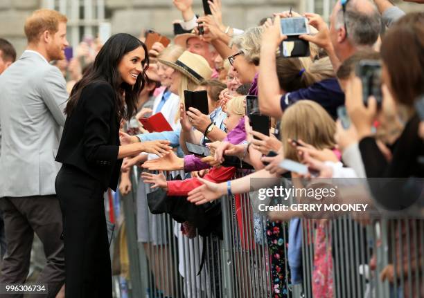 Britain's Meghan, Duchess of Sussex and Britain's Prince Harry, Duke of Sussex greet well-wishers after their visit to Trinity College in Dublin on...