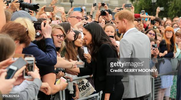 Britain's Meghan, Duchess of Sussex and Britain's Prince Harry, Duke of Sussex greet well-wishers after their visit to Trinity College in Dublin on...