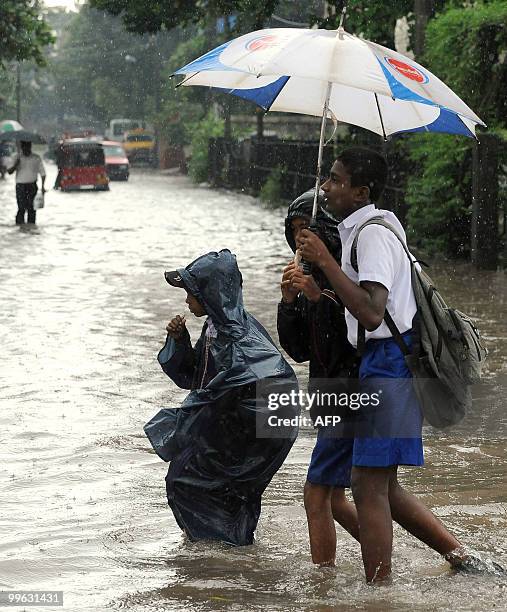 Sri Lankan school children walk along a flooded road in Colombo on May 17, 2010. Several days of heavy rain coupled with strong winds and lightening...