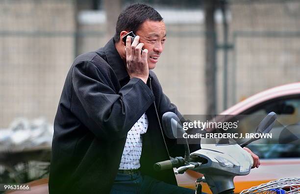 Man speaks on his mobile phone while riding a scooter along a street in Beijing on May 17, 2010. The largest study to date of the safety of mobile...