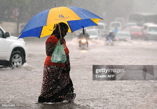 Sri Lankan woman walks along a partially submerged road in Colombo on May 17, 2010. Several days of heavy rain coupled with strong winds and...