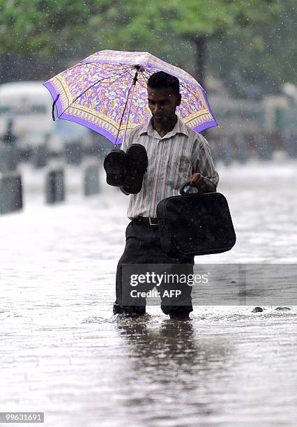 Sri Lankan man walks along a flooded road in Colombo on May 17, 2010. Several days of heavy rain coupled with strong winds and lightening marked the...