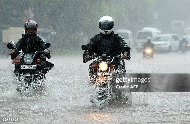 Two Sri Lankan motorcyclists ride along a partially submerged road in Colombo on May 17, 2010. Several days of heavy rain coupled with strong winds...