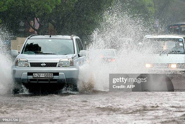 Vehicles drive along a partially submerged road in Colombo on May 17, 2010. Several days of heavy rain coupled with strong winds and lightening...