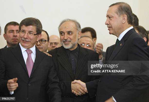 Turkish Prime Minister Recep Tayyip Erdogan shakes hands with Iran's Nuclear Chief Ali Akbar Salehi as Turkey's Foreign Minister Ahmet Davutoglu...