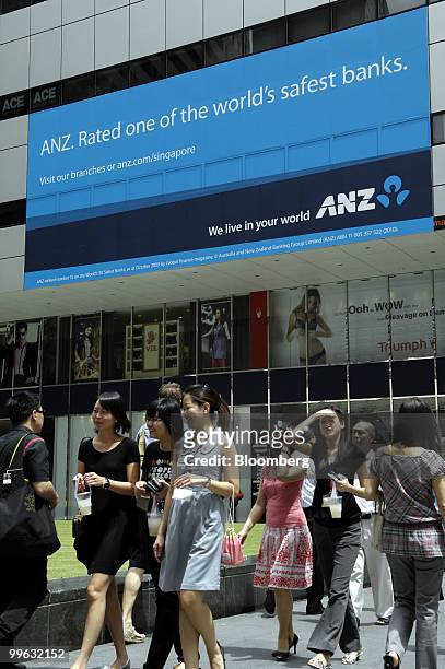 Pedestrians walk past an advertisement for Australia & New Zealand Banking Group Ltd. In the central business district in Singapore, on Monday, May...