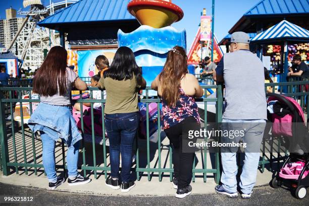 People watch children on an amusement ride at Luna Park in Coney Island in the Brooklyn Borough of New York, U.S., on Saturday, July 7, 2018....