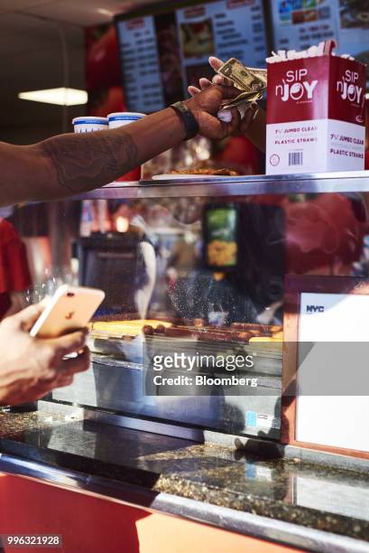Customer purchases a slice of pizza from a food vendor on the Coney Island boardwalk in the Brooklyn Borough of New York, U.S., on Saturday, July 7,...