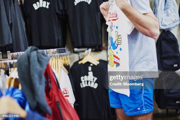 Shopper views a Nathan's famous Inc. Souvenir shirt for sale at a shop on the Coney Island boardwalk in the Brooklyn Borough of New York, U.S., on...