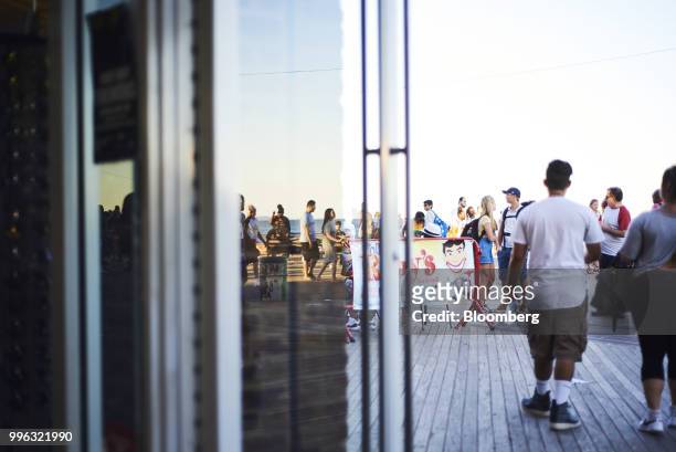 Pedestrians pass in front of Rudy's Bar & Grill on the Coney Island boardwalk in the Brooklyn Borough of New York, U.S., on Saturday, July 7, 2018....