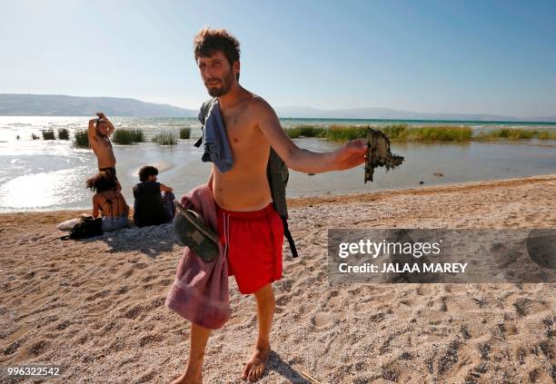 An Israeli man holds debris as Israeli forces search the Sea of Galilee coasts for the remains of a reported drone launched from Syria and...