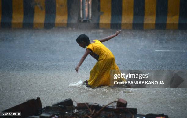 An Indian girl walks on a road during heavy rain showers in Allahabad on July 11, 2018.