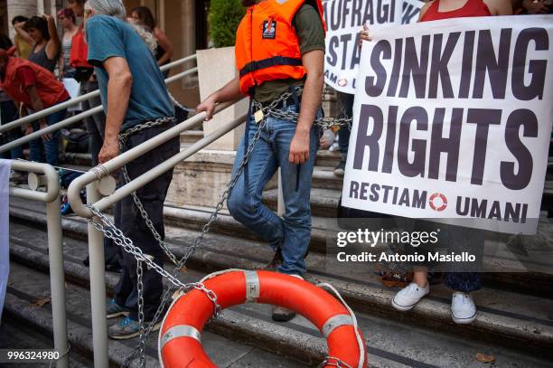 Dozens of protesters wearing life jackets chained themselves outside the Ministry of Transport during a protest against the Italian immigration...