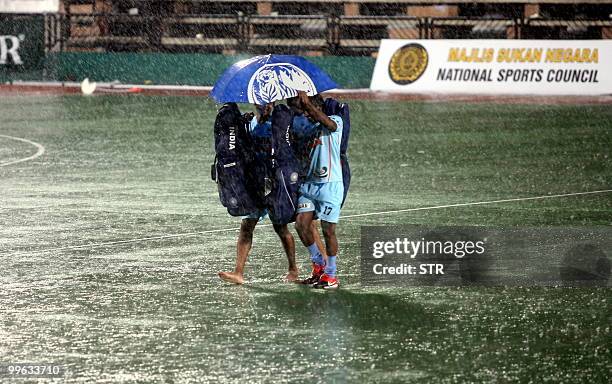 Indian field hockey players leave the pitch amid heavy rain following their final match against South Korea during the 19th Sultan Azlan Shah Cup...