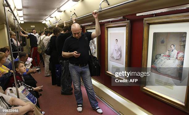 People ride the subway transit vehicle with reproductions of a watercolours of the Pushkin Museum of Fine Arts collection in Moscow on May 12, 2010....