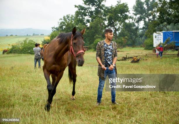 young gypsy man with his horse participating in the the traditional annual national festivity in the neighborhood of baba kondu in the municipality of targovishte, bulgaria - national career fairs imagens e fotografias de stock