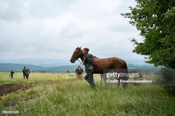 young roma men (gypsies) participating in a horse competition during the traditional national festivity in the neighborhood of baba kondu in the municipality of targovishte, bulgaria - pavel gospodinov stockfoto's en -beelden