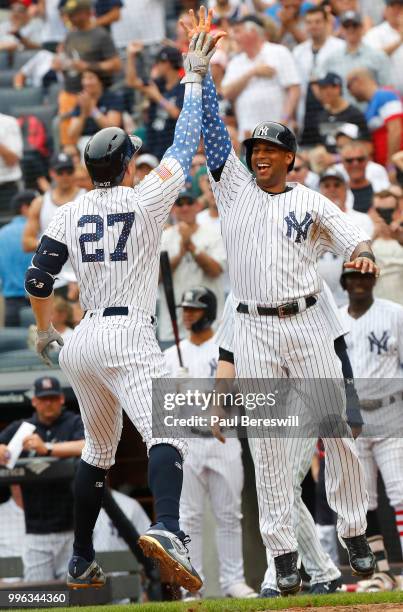Aaron Hicks of the New York Yankees greets teammate Giancarlo Stanton after Stanton crossed the plate with his home run in an interleague MLB...