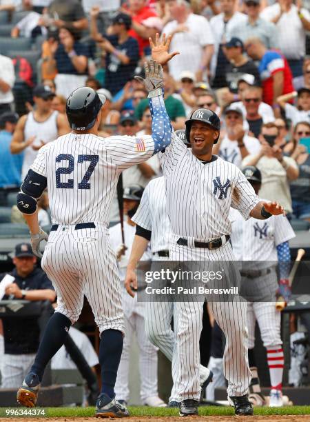 Aaron Hicks of the New York Yankees greets teammate Giancarlo Stanton after Stanton crossed the plate with his home run in an interleague MLB...