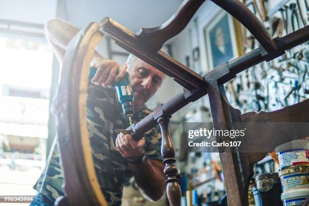 timmerman herstel van een oude houten stoel - carlo107 stockfoto's en -beelden