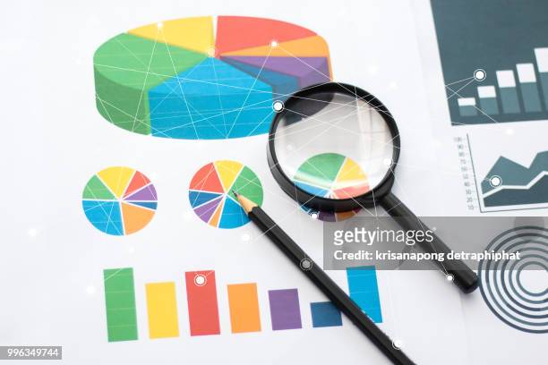 magnifying glass and pen on graphs - marktforschung stock-fotos und bilder