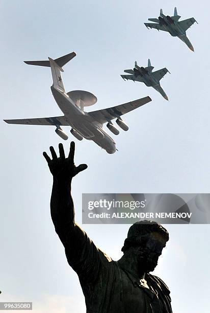 Russian A-50 plane and Su-27 fighter jets fly a statue of Russian historical figures Minin and Pozharsky near St. Basil's Cathedral on Red Square in...