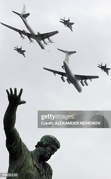 Russian MiG-29, Il-78, and Tu-95 planes fly over a statue of Russian historical figures Minin and Pozharsky on Red Square during a Victory Day parade...